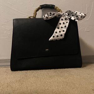 Chic black handbag, With white polkadot scarf.